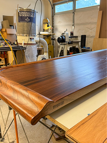 Live-edge walnut bar top photographed in the workshop before delivery, with the curved chamfered edge in profile